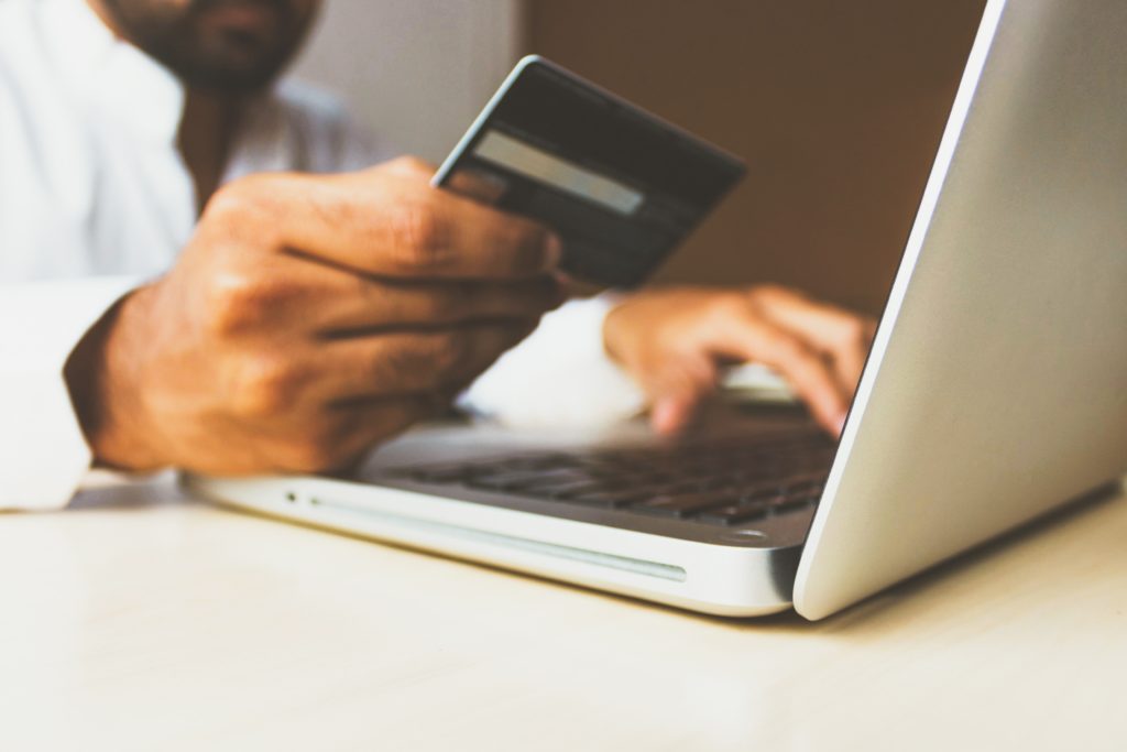 person holding their credit card making a purchase on their laptop