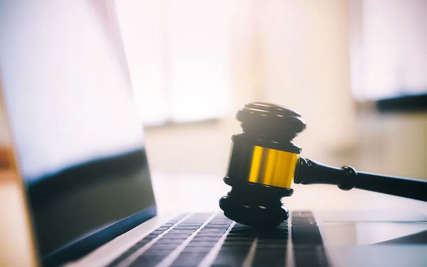 A judge gavel on the keyboard of an open laptop
